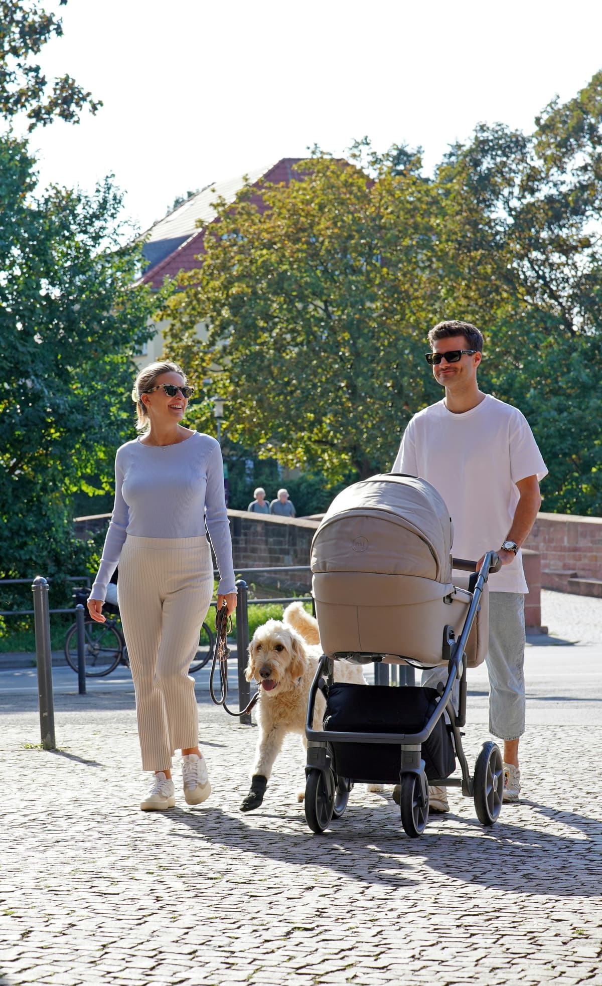 Familia feliz paseando con coche de bebé